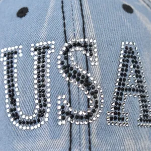 Gros plan detail de casquette de baseball en jean strass lettres USA et texture brillante.