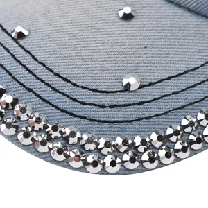 Gros plan détaillé d'une casquette de baseball en jean bleu clair ornée de strass argentés et coutures.