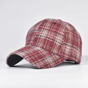 Red plaid winter baseball cap detail showing fabric texture, classic patterned curved brim hat.