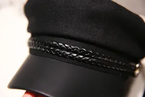 Black baker boy hat detail showing braided strap and leather visor, stylish British retro cap.