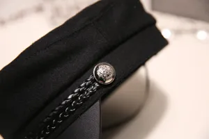 Classic black baker boy hat with braided leather strap and metal button, retro newsboy cap.