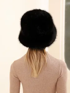 Detail view of black fluffy fox fur bucket hat worn on model with beige knitted top.