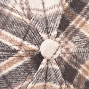 Detailed view of winter plaid cap fabric texture and top button craftsmanship close up.