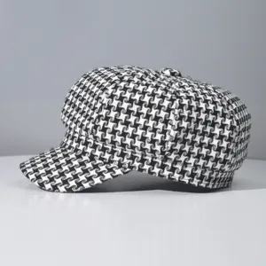 Detailed view of black and white houndstooth newsboy cap, classic geometric pattern fabric.