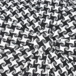 Close-up detail shot of classic black and white houndstooth fabric texture cap top button.