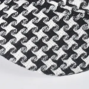 Close-up of black and white houndstooth fabric texture, classic retro pattern detail.