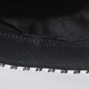 Close-up detail of black hat band with houndstooth trim showing fine texture and stitching.