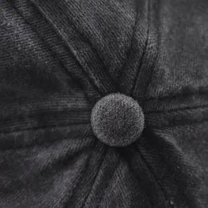 Close-up detail shot of the washed denim docker cap top button and precision stitching.