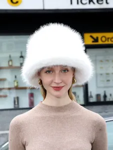 Detailed view of a fluffy white winter fur bucket hat worn by a model outdoors in style.