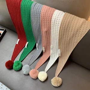 Detailed view of women's knitted hollow triangle scarf featuring plush pom pom, cozy winter accessory.