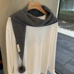 Detailed view of the dark grey knitted triangle scarf with cute pompom and wool blend.