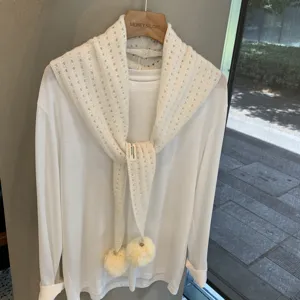 White hollow knit scarf shawl detail showing pom pom and premium woolen texture layering.