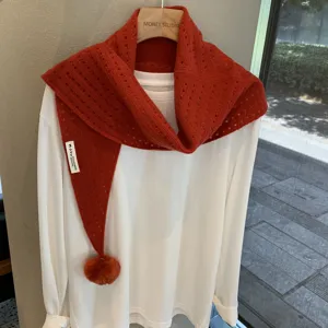 Orange-red knit triangular scarf with pom-pom detail, hollow wool shawl for women layering.