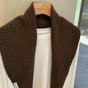 Brown knit hollow shawl scarf detail shot, cozy autumn winter layering accessory texture.