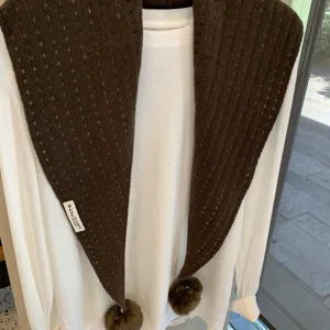 Detailed view of the brown knitted triangle scarf featuring delicate hollow-out patterns and pom.