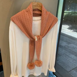 Chic knitted triangular scarf with cute pom pom details, perfect for autumn winter layered outfits.