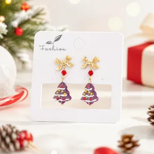 Boucles d'oreilles sapin de Noël en verre vue détaillée avec nœud doré et ambiance.