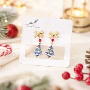 Gros plan détaillé des boucles d'oreilles sapin de Noël en verre avec un nœud doré.
