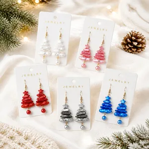 Close-up of colorful imitation pearl Christmas tree earrings on cards with holiday pine decor.