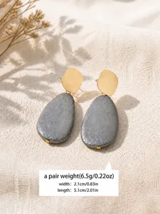 Detailed shot of vintage textured grey drop earrings with gold geometric top, elegant style.