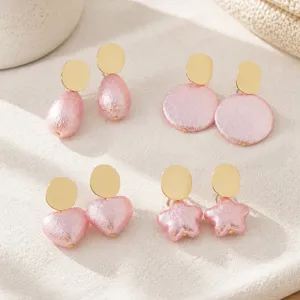 Detailed shot of pink pearlescent crinkled earrings featuring geometric shapes like hearts and stars.