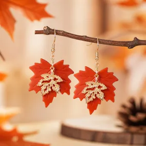 Detailed close-up of double layer maple leaf earrings hanging on branch with autumn background.