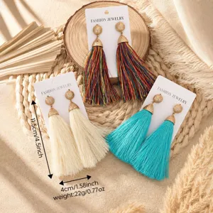 Close-up detail of bohemian long tassel earrings with metallic top studs and vibrant threads.
