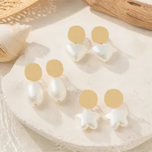 Detailed close-up view of French style gold disc and textured faux pearl drop earrings.
