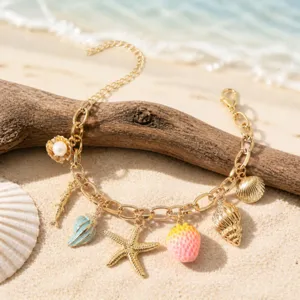 Detailed shot of gold charm bracelet featuring coastal elements like starfish and shells.