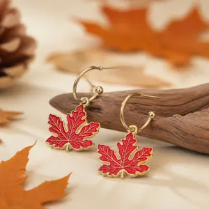 Close-up detail of autumn red maple leaf earrings with vintage gold rim and hoop hook design.