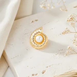 Close-up detail of the vintage gold spiral shell pearl cufflink on textured stone background.