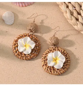 Handgemaakte rattan oorbellen met witte bloem detail, perfecte vakantie stijl accessoire.