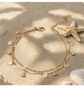 Chaîne de cheville dorée à double couche avec strass et pendentifs pièces, bijoux élégants.