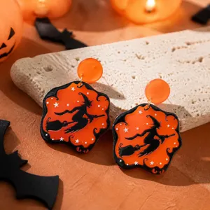 Gedetailleerde close-up van Halloween acryl heks oorhangers met oranje en zwart ontwerp.