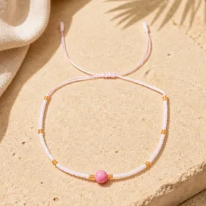 Gros plan sur le bracelet de perles roses bohème avec perle en pierre centrale et cordon réglable.