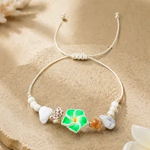 Gros plan détail du beau bracelet cordon tressé fait main avec une fleur en argile verte.
