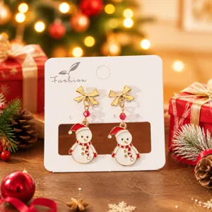 Détail des boucles d'oreilles bonhomme de neige de Noël avec nœud doré et design festif.