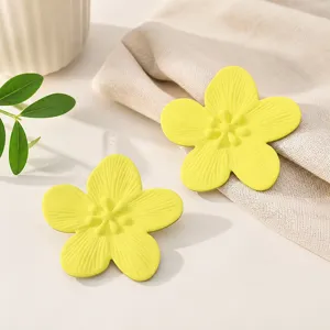 Detailaufnahme gelber Blumenohrringe, niedliches fünfblättriges Design mit feiner Textur.