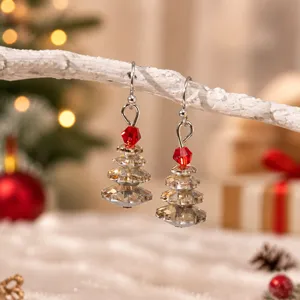 Gros plan détaillé de boucles d'oreilles sapin de Noël en cristal scintillantes sur branche.