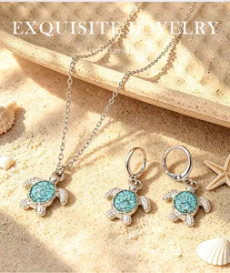 Detailed close-up of turquoise turtle necklace and earrings set on sandy beach background.