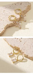 Boucles doreilles creoles en zirconia plaque or avec pendentifs croix et baguette.