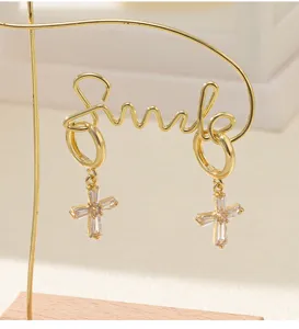 Vue détaillée des boucles d'oreilles croisées en zircon doré avec un design filaire Smile.