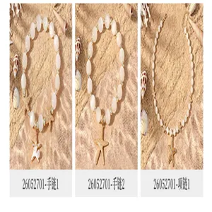 Nahaufnahme von Perlenarmbändern und Halskette mit Seestern-Anhängern auf Sandhintergrund.