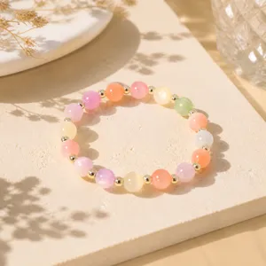 Bunte Perlenarmband Detailaufnahme, Pastellfarbene transluzente Steine mit goldenen Metallperlen.
