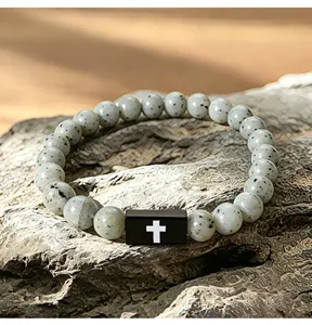 Close-up detail van heren steen kralen armband met zwarte rechthoekige kruis bedel elastisch