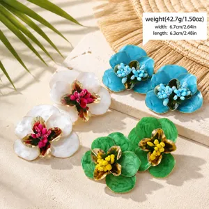 Vue de détail en gros plan de boucles d'oreilles fleurs émail avec finition dorée.