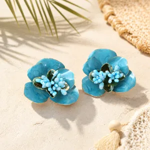 Vue détaillée de boucles d'oreilles florales en émail bleu avec design d'étamines délicat.