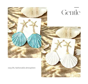 Detail view of resort style starfish and seashell alloy earrings in blue and white colors.
