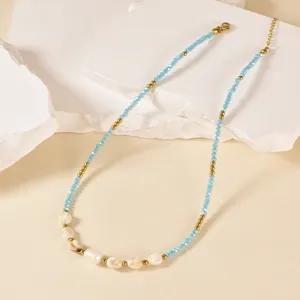 Close-up detail of handmade beaded necklace featuring freshwater pearls and blue glass beads.