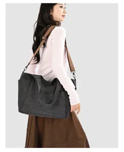 Detail view of large capacity canvas shoulder bag in dark grey, featuring sturdy brown straps.